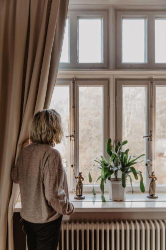 a woman is looking out of a window at Hotel Slottsvillan in Huskvarna