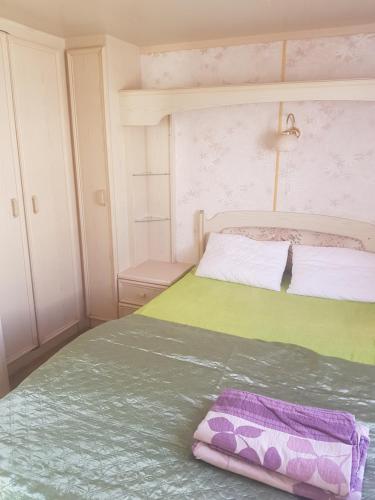 a bedroom with a bed with a purple and green blanket at Rodzinne Domki Łeba in Łeba