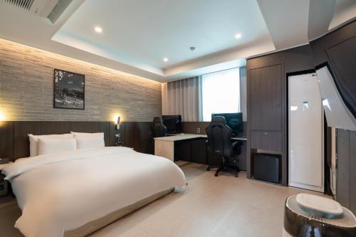 a hotel room with a large bed and a desk at Jecheon Hound Hotel in Jecheon