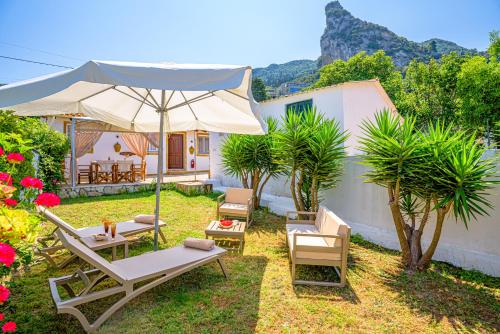 a patio with lounge chairs and an umbrella at Elena's Seaside Apartments & Studios in Agios Gordios