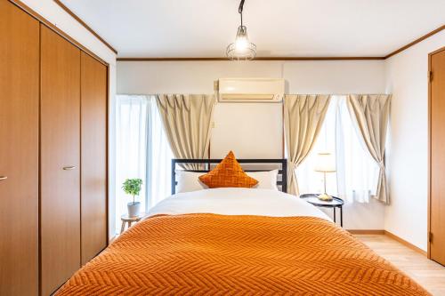 a bedroom with a bed with an orange blanket at アリタハイツ難波311 in Osaka