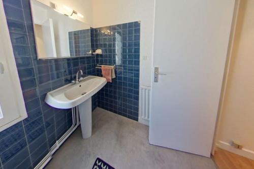 a blue tiled bathroom with a sink and a mirror at RÉF 119 LARMOR-PLAGE Appartement studio moderne in Larmor-Plage