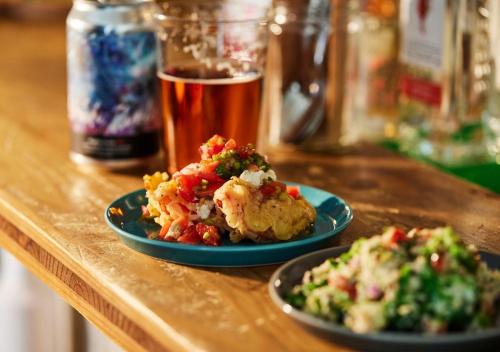 a table with two plates of food and a glass of beer at Hotel Graphy Nezu in Tokyo