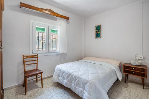 1 dormitorio con 1 cama, 1 silla y 1 ventana en Casa Juan y Loli, en Nigüelas