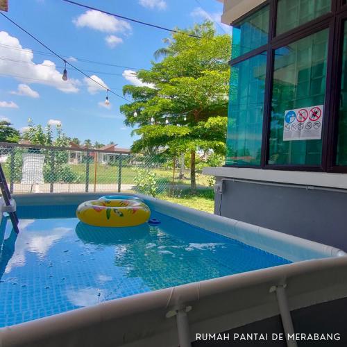 a swimming pool with a yellow raft in the water at Rumah Pantai de Merabang (bungalow with pool) in Bachok