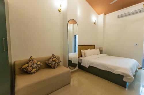 ein Schlafzimmer mit einem Bett, einem Spiegel und einem Sofa in der Unterkunft Oceanature Alibaug in Alibag