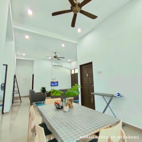 a dining room with a table and a ceiling fan at Rumah Pantai de Merabang (bungalow with pool) in Bachok