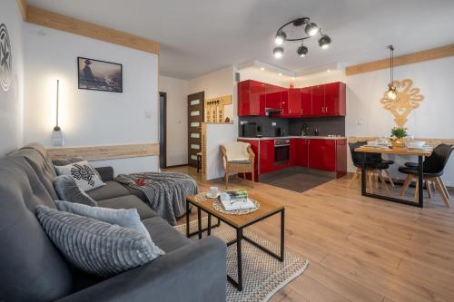 ein Wohnzimmer und eine Küche mit roten Schränken in der Unterkunft ZakoApartament Brzozowa in Zakopane