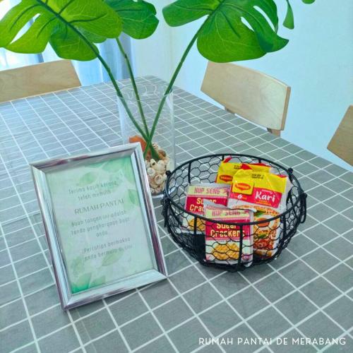 a basket of food on a table next to a sign at Rumah Pantai de Merabang (bungalow with pool) in Bachok