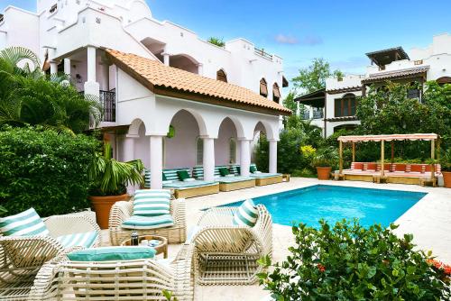a swimming pool with chairs and a house at Cap Maison Resort & Spa in Cap Estate