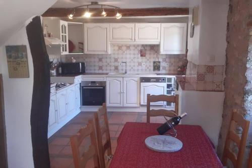 a kitchen with white cabinets and a table with a wine bottle on it at LA PASTOURELLE in Saint-Chinian