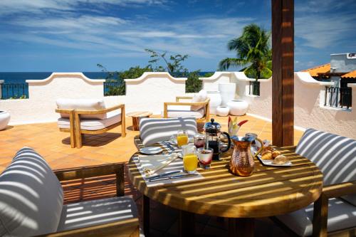a wooden table with glasses of orange juice on a patio at Cap Maison Resort & Spa in Cap Estate