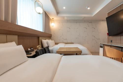 a hotel room with two beds and a table at Jecheon Hound Hotel in Jecheon