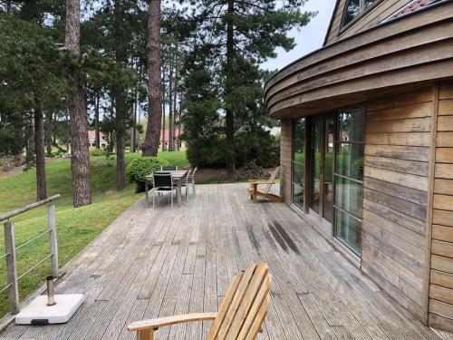 une terrasse en bois avec deux chaises et un bâtiment dans l'établissement Maison d'architecte sur le golf d'Hardelot, à Neufchâtel-Hardelot