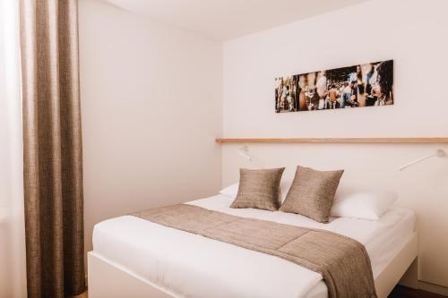 a bedroom with a bed with white sheets and pillows at Vina Kobal, Kobal Family Estate in Štanjel