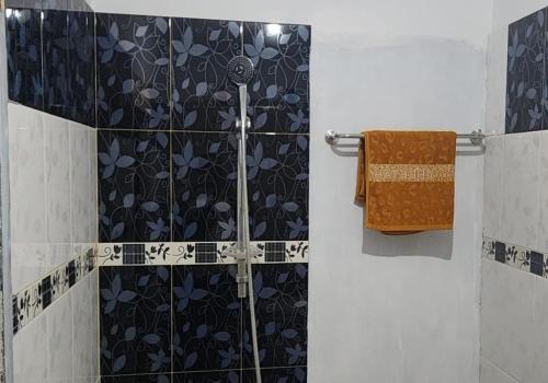 a bathroom with a shower with a black and white tiles at Permata Homestay Kotamobagu Mitra RedDoorz in Poyowa-besar