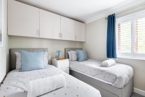two beds in a bedroom with white walls and blue curtains at Hideaway - Exclusive marina development, town centre, with parking in Falmouth