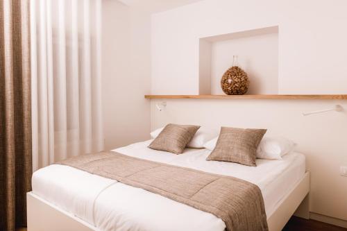 a bedroom with a bed with white sheets and a mirror at Vina Kobal, Kobal Family Estate in Štanjel