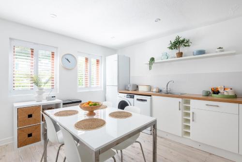 a white kitchen with a white table and chairs at Hideaway - Exclusive marina development, town centre, with parking in Falmouth