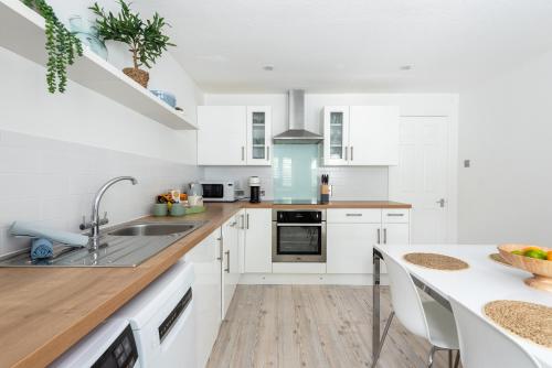 a kitchen with white cabinets and a sink at Hideaway - Exclusive marina development, town centre, with parking in Falmouth
