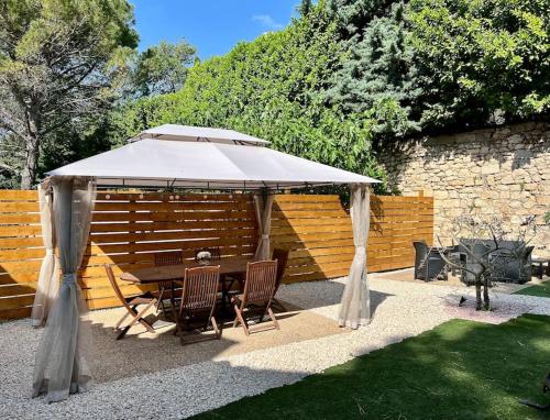 a table and chairs under an umbrella in a garden at La Maison d'Elisa in Les Baux-de-Provence