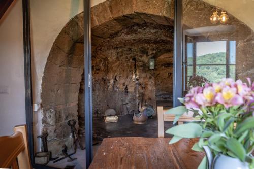 a dining room with a table and a stone wall at Antica Porta di Sovana 2.0 in Pitigliano