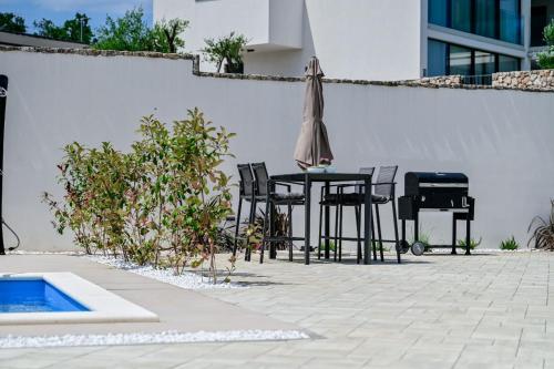 a patio with a table and chairs and an umbrella at Apartments Lena in Malinska
