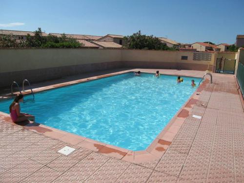- une piscine avec des personnes assises dans l'eau dans l'établissement Villa T2 Mezzanine 6 pers avec Jardin, Piscine, Proche Plage - Saint-Cyprien - FR-1-106-27, à Saint-Cyprien