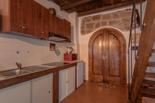 a kitchen with a sink and a wooden door at Antica Porta di Sovana 2.0 in Pitigliano