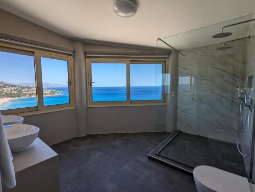 a bathroom with two sinks and a shower with a view of the ocean at Villa Blue Dream in Koutsounari