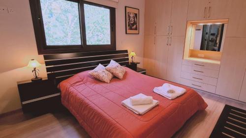 a bedroom with a red bed with two towels on it at STAY Efrosini Country House in Moniatis