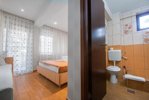 a bathroom with a bed and a toilet in a room at Vila Puky in Neptun