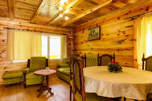 - un salon avec une table et des chaises dans une cabane en rondins dans l'établissement Brvnare 3 zvezde brvnara Veljko, à Kokin Brod