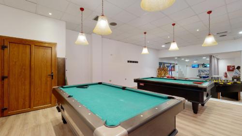 a billiard room with two pool tables and pendant lights at Acrotel Athena Pallas in Elia