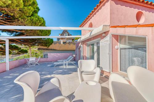 a patio with white chairs and a pink house at The Pink Elephant Hotel in S'Agaro