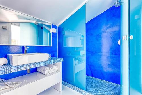a blue bathroom with a sink and a shower at The Pink Elephant Hotel in S'Agaro