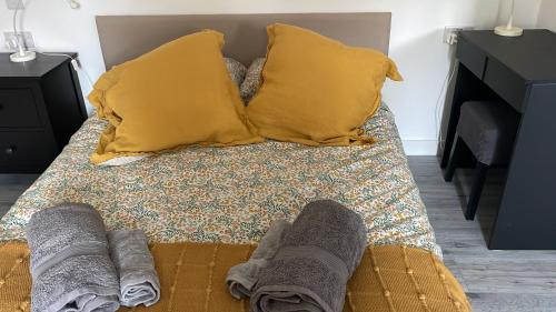 ein Bett mit zwei gelben Kissen und den Füßen einer Person darauf in der Unterkunft Studio - Sleeps 2 - Pet friendly - Parking in Hendon