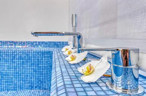 a bathroom with white flowers on a blue tiled counter at The Pink Elephant Hotel in S'Agaro