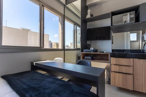 a room with a desk and a kitchen with windows at Studio confortável e moderno - Vn Vergueiro próximo a hospitais, universidades, a av Paulista e em frente ao centro cultural SP - excelente localização - ap 1515 in Sao Paulo
