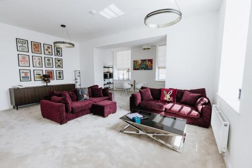a living room with two purple couches and a table at Grade II Mill Townhouse in Leeds with Free Parking which Sleeps 6 in Leeds