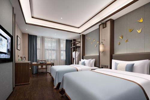 a hotel room with three beds and a television at Till Bright Hotel, Loudi Shuangfeng in Shuangfeng