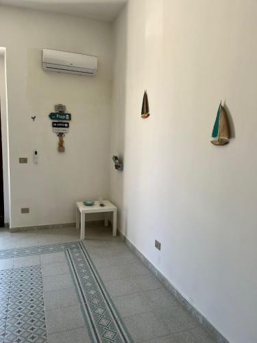 a room with a table and a white wall at A 2 passi dal mare - grazioso trilocale a Locri in Locri