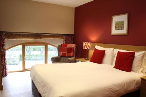 StocksbridgeにあるUnsliven Bridge Farmの大きなベッドと椅子が備わるホテルルームです。