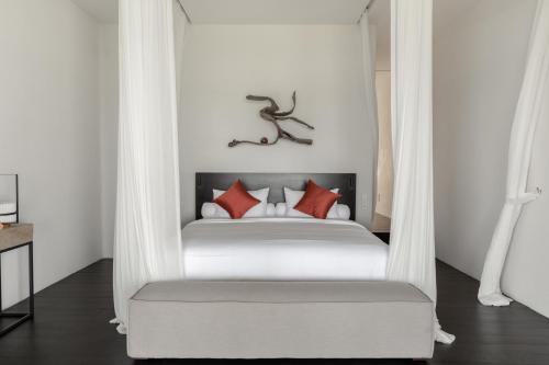 a bedroom with a white bed with red pillows at The Jing in Tejakula