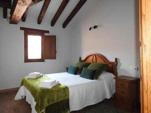 a bedroom with a bed with white sheets and green pillows at CASUCA LA SOLANA in Potes