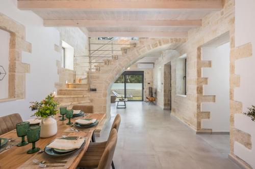 a dining room with a table and a stone wall at Megalith Villas in Nea Kydonia