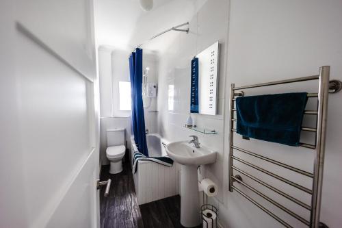a white bathroom with a sink and a toilet at Flat 3 Flint House Tenby - Luxury couples apartment in Tenby
