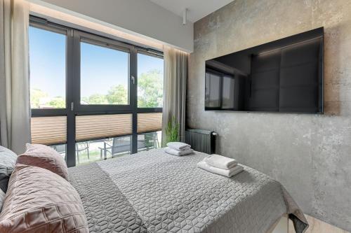 a bedroom with a bed and a flat screen tv at GRANO FLATS - Sobieszewo - Baltic Porto in Gdańsk