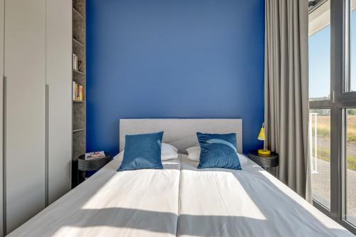 a blue bedroom with a large bed with blue walls at GRANO FLATS - Sobieszewo - Baltic Porto in Gdańsk