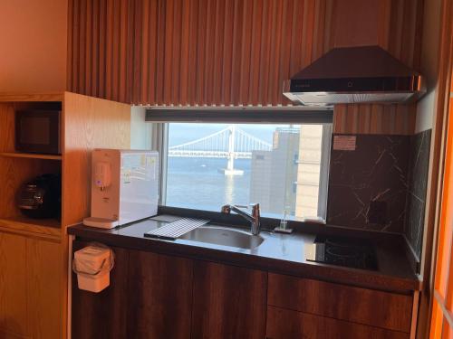 a kitchen with a sink and a window with a bridge at Gwanganli The Club Hotel in Busan